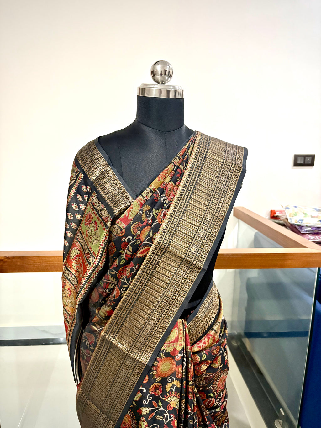 Elegant Saree Featuring a Rich Black Base with Incricate Floral and Motifs in Warm Gold, Rust and Beige Tones with Antique Gold Zari Weaving Border.