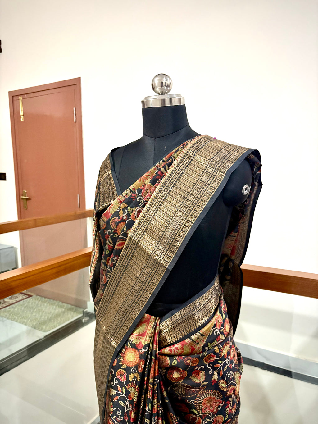 Elegant Saree Featuring a Rich Black Base with Incricate Floral and Motifs in Warm Gold, Rust and Beige Tones with Antique Gold Zari Weaving Border.