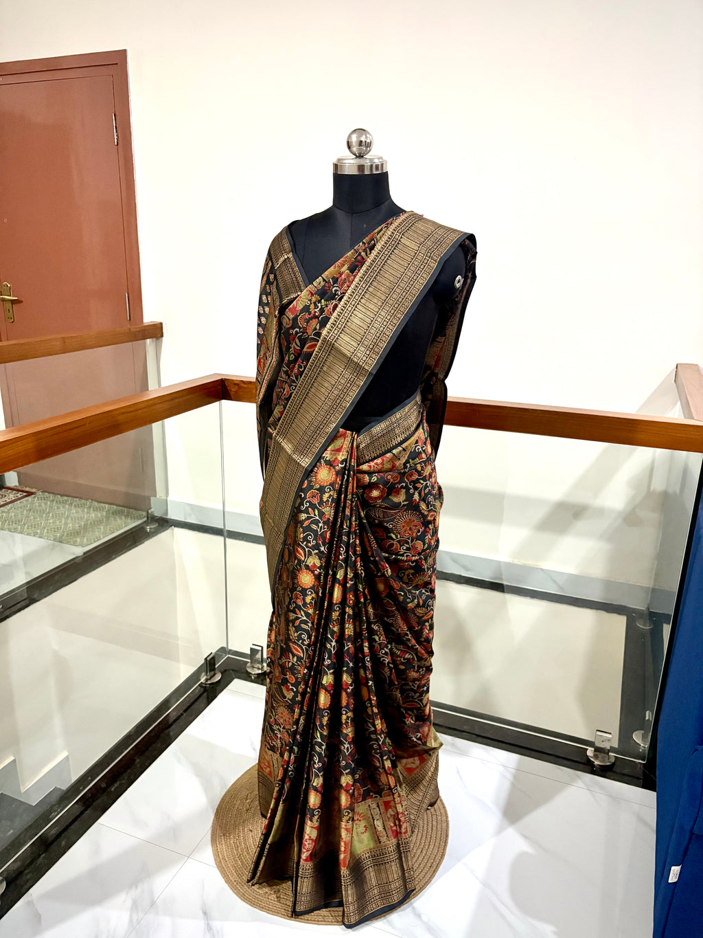 Elegant Saree Featuring a Rich Black Base with Incricate Floral and Motifs in Warm Gold, Rust and Beige Tones with Antique Gold Zari Weaving Border.