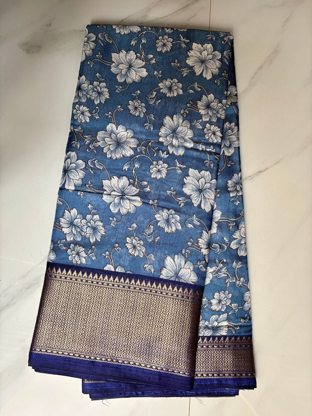 Elegant blue floral printed saree, beautifully adorned with delicate white blossom motifs and complemented by a rich navy blue zari border- Cotton tissue soft Saree