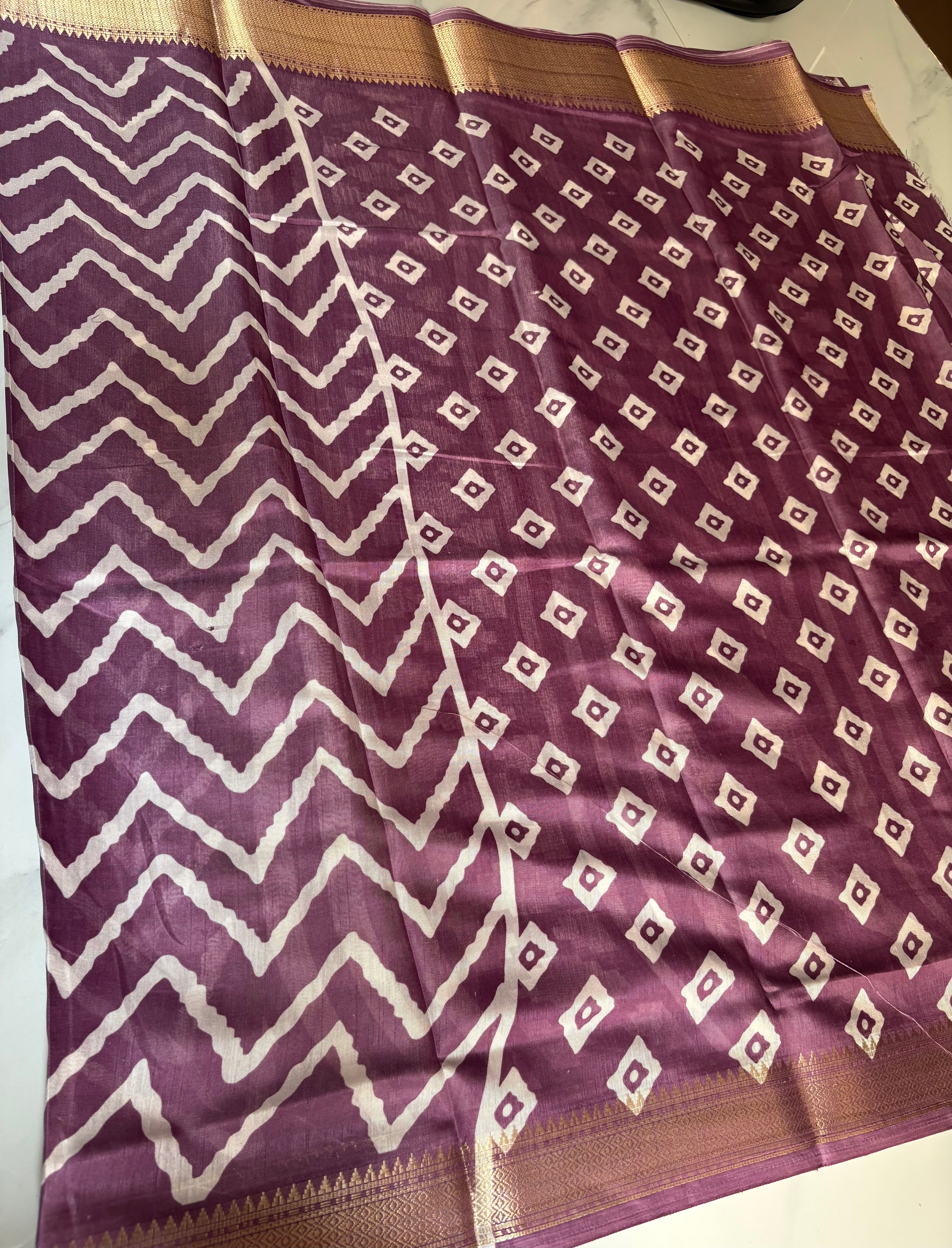 Elegant purple printed saree featuring bold white zigzag patterns and a rich zari border - Cotton tissue soft Saree