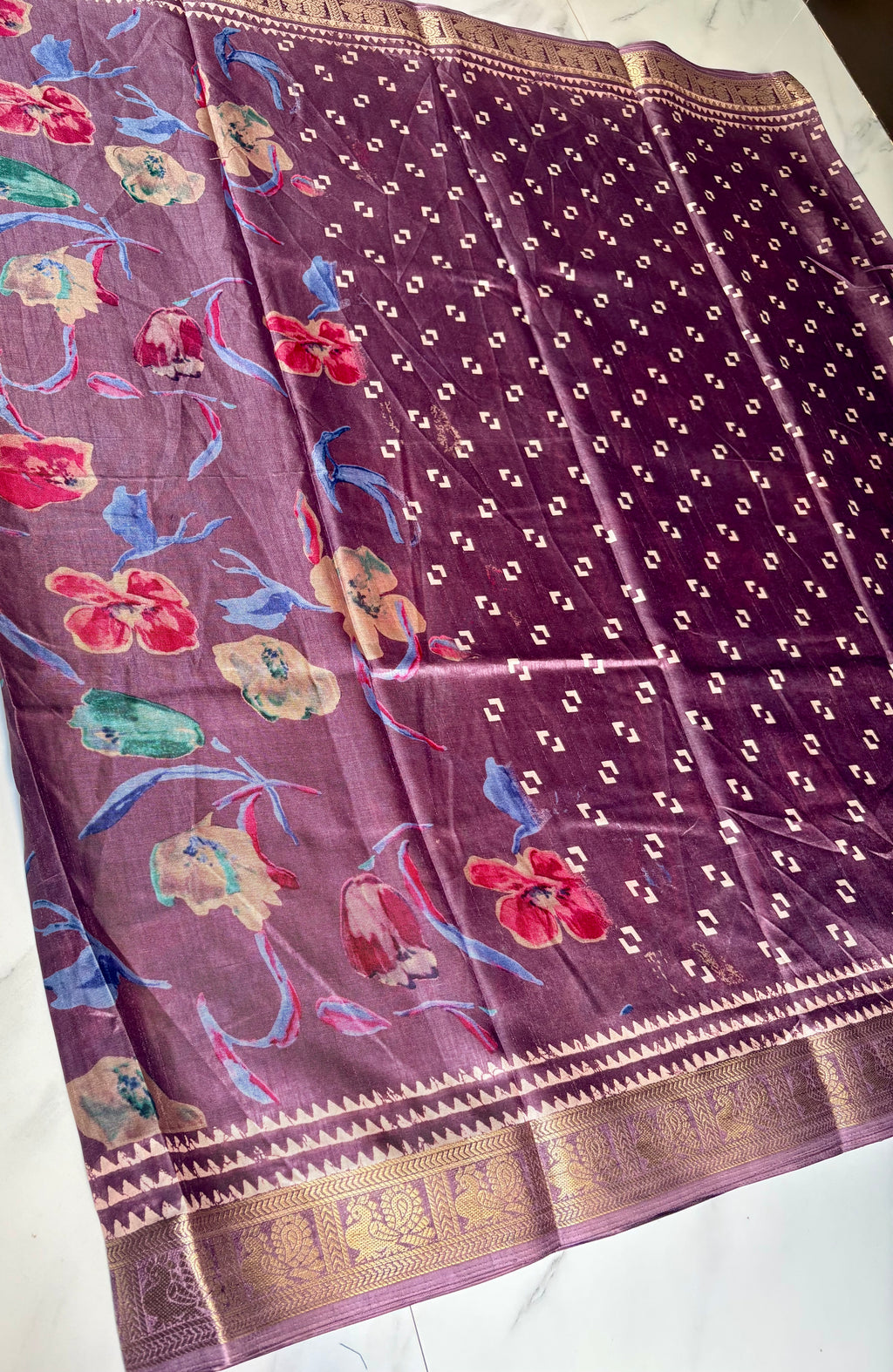 Elegant mauve-purple saree featuring a graceful floral print in vibrant shades of red, blue, and green. Accentuated with a rich golden woven border - Satin Tissue Saree