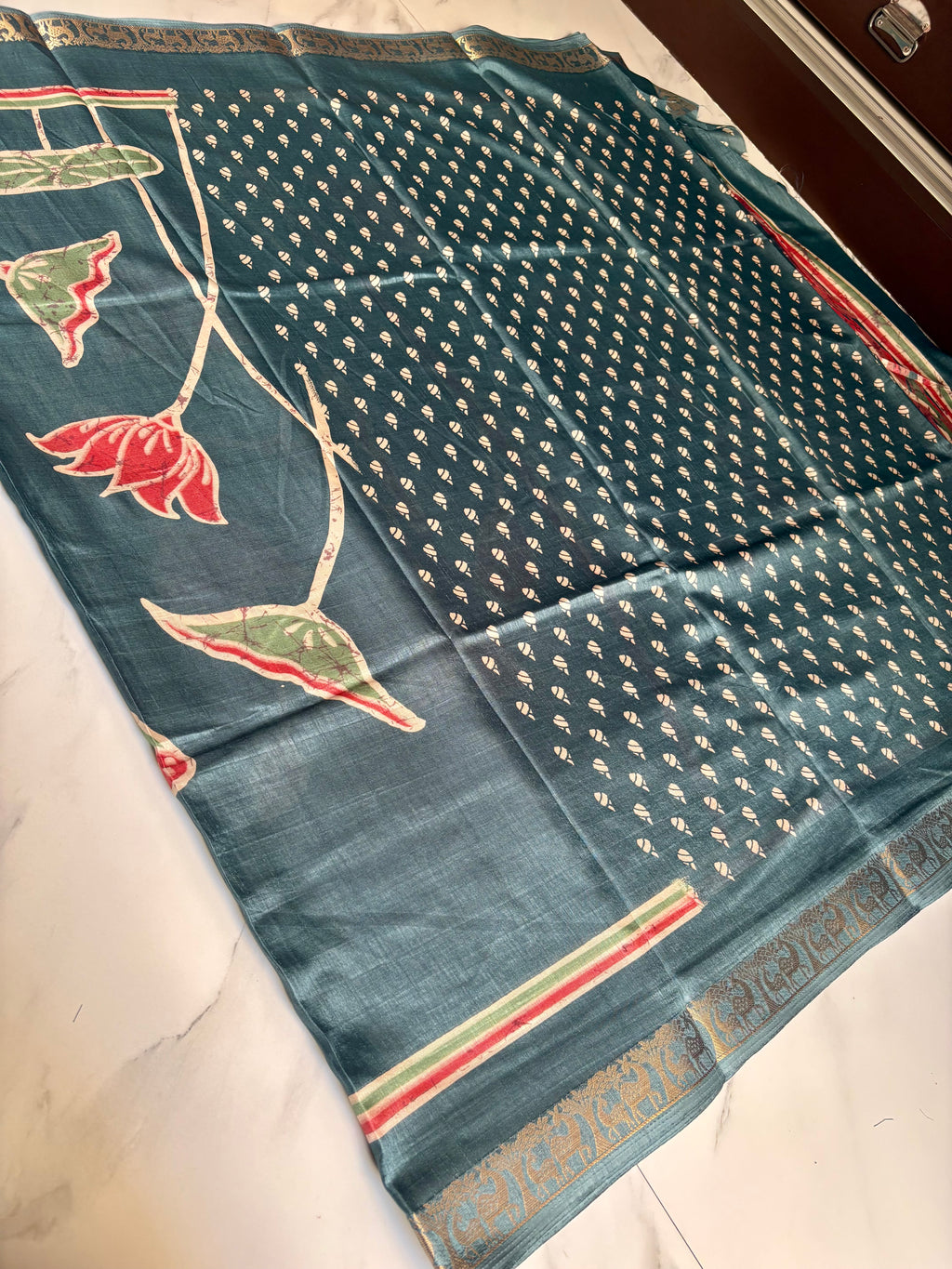 Elegant teal blue saree featuring a graceful lotus floral print with a beautifully woven golden elephant motif border - Satin Tissue Saree
