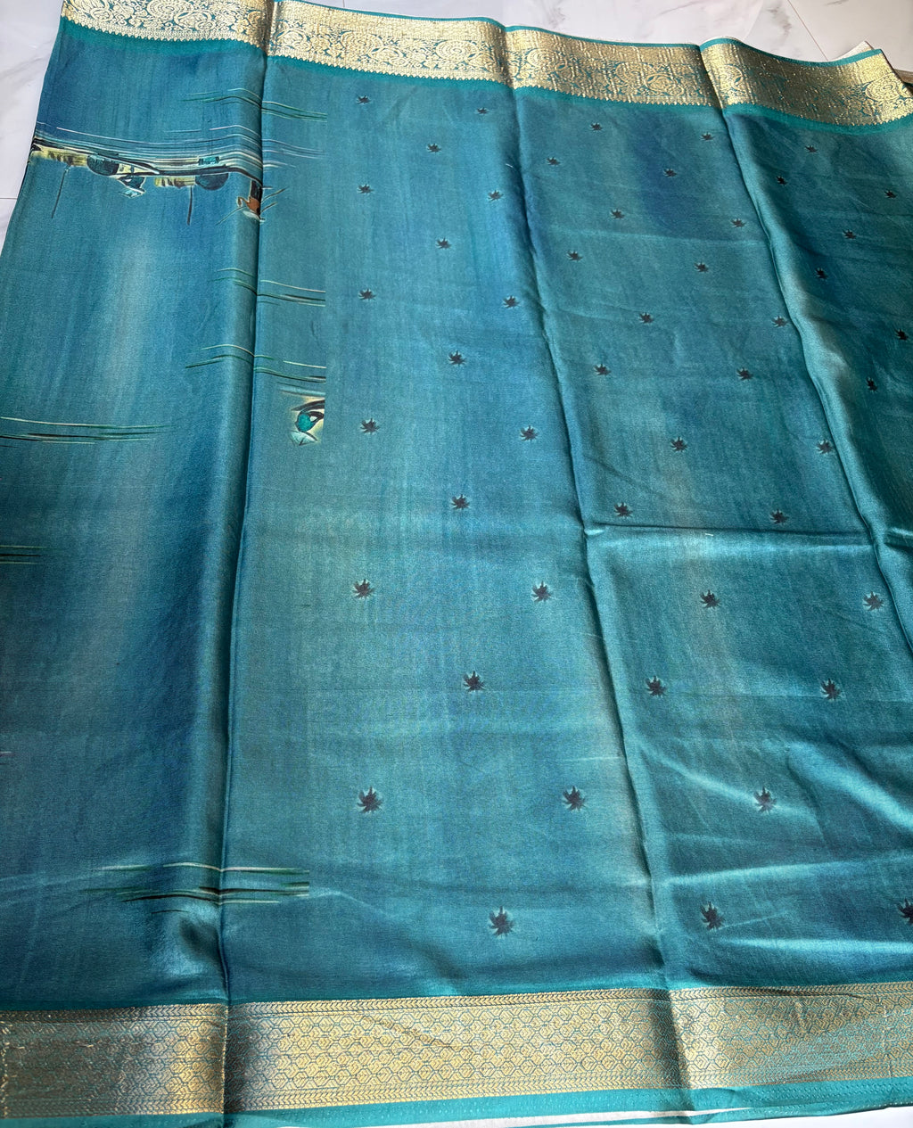 Elegant teal blue featuring a serene village landscape print designs with rich woven zari border - Satin Tissue Saree