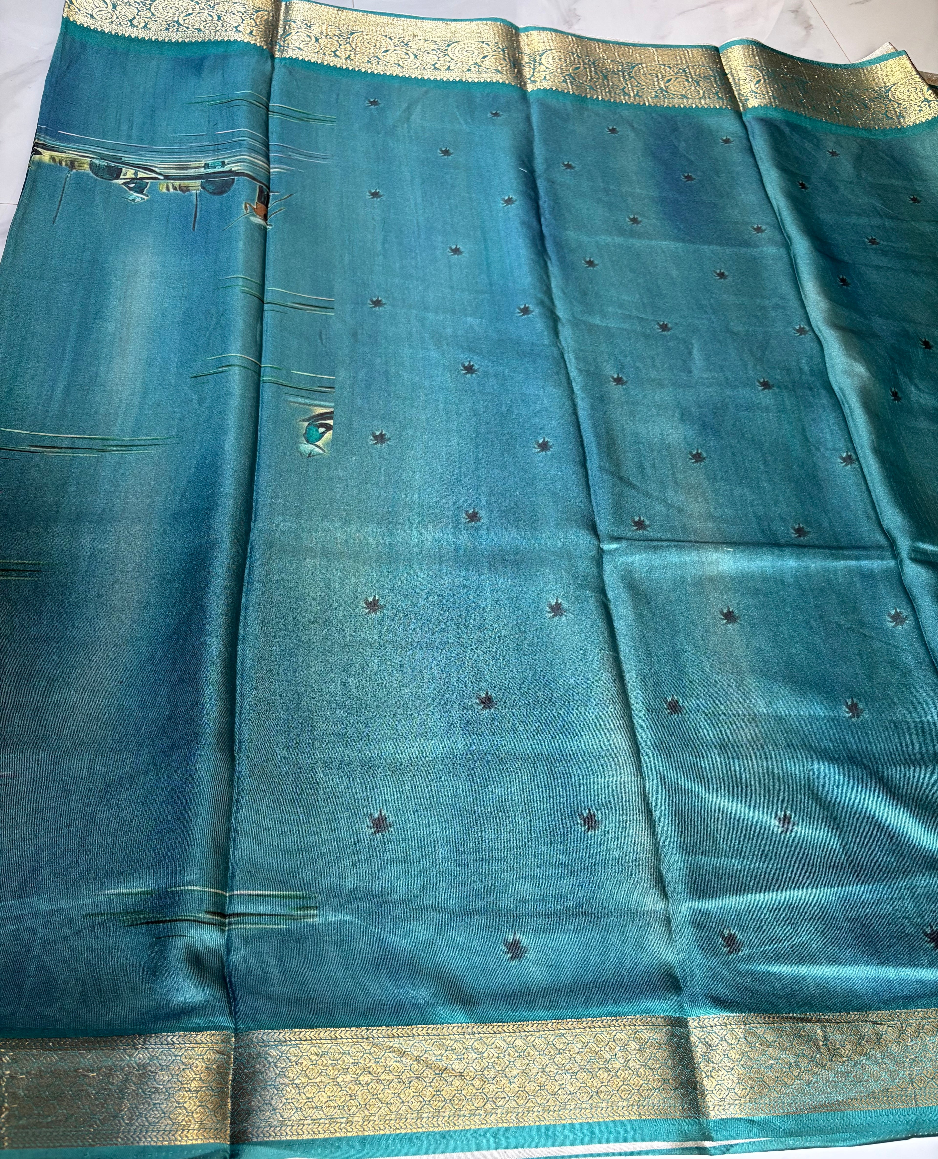 Elegant teal blue featuring a serene village landscape print designs with rich woven zari border - Satin Tissue Saree