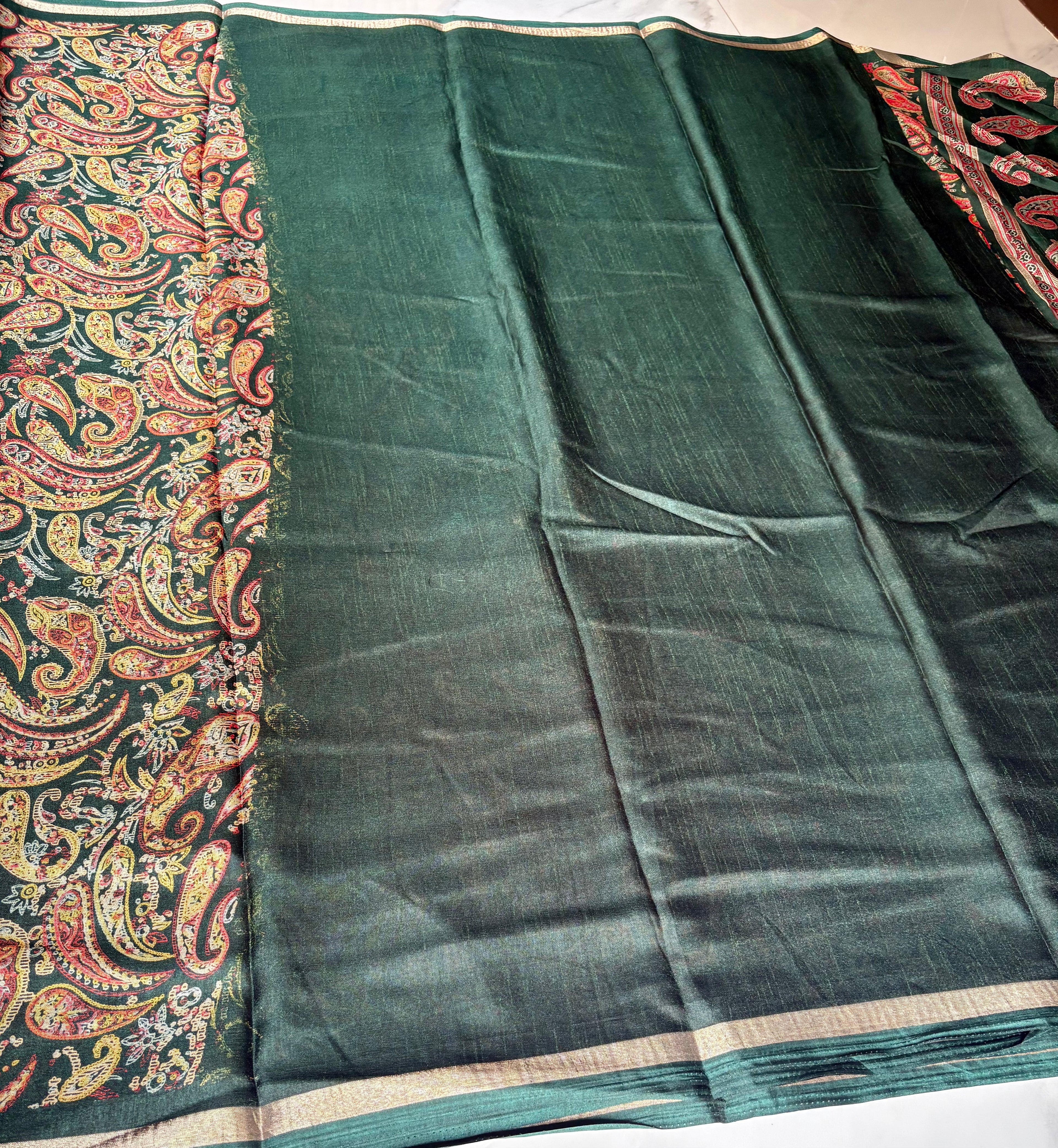 Elegant dark green saree featuring intricate multicolor paisley prints and subtle golden edging.