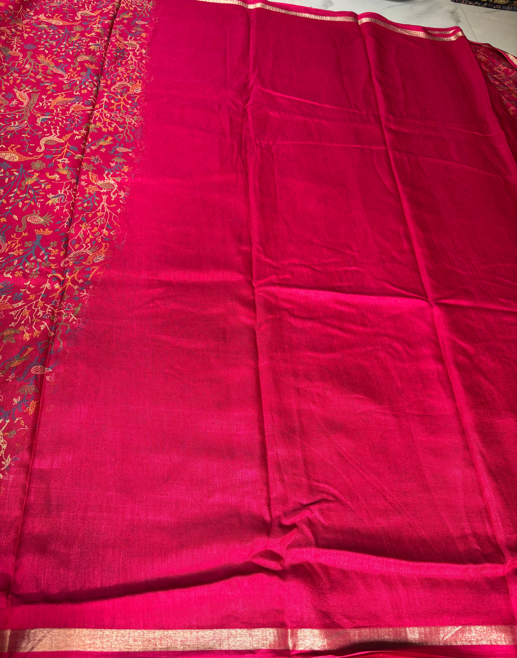 Elegant crimson red saree adorned with intricate heritage-inspired motifs and subtle golden edging.