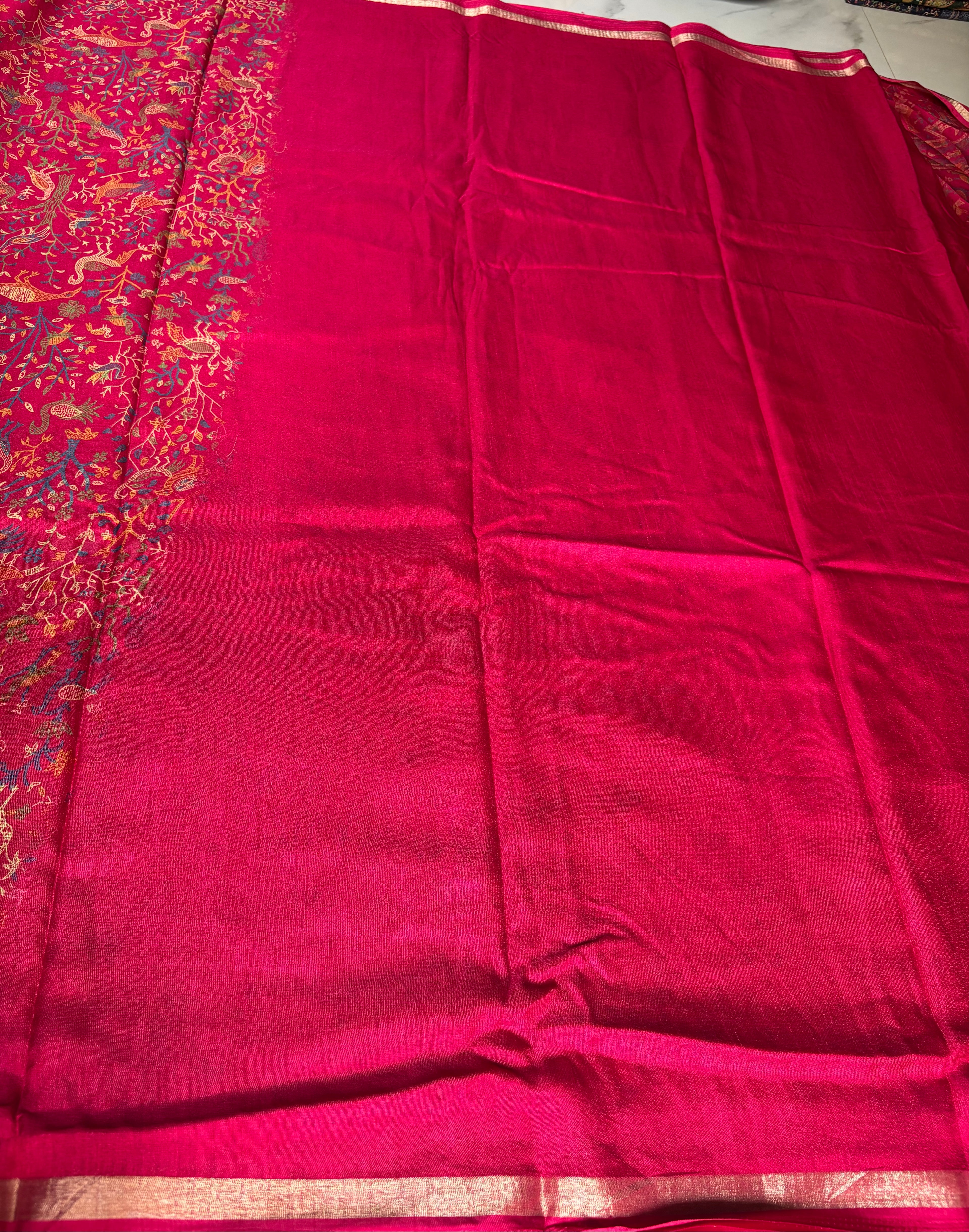 Elegant crimson red saree adorned with intricate heritage-inspired motifs and subtle golden edging.