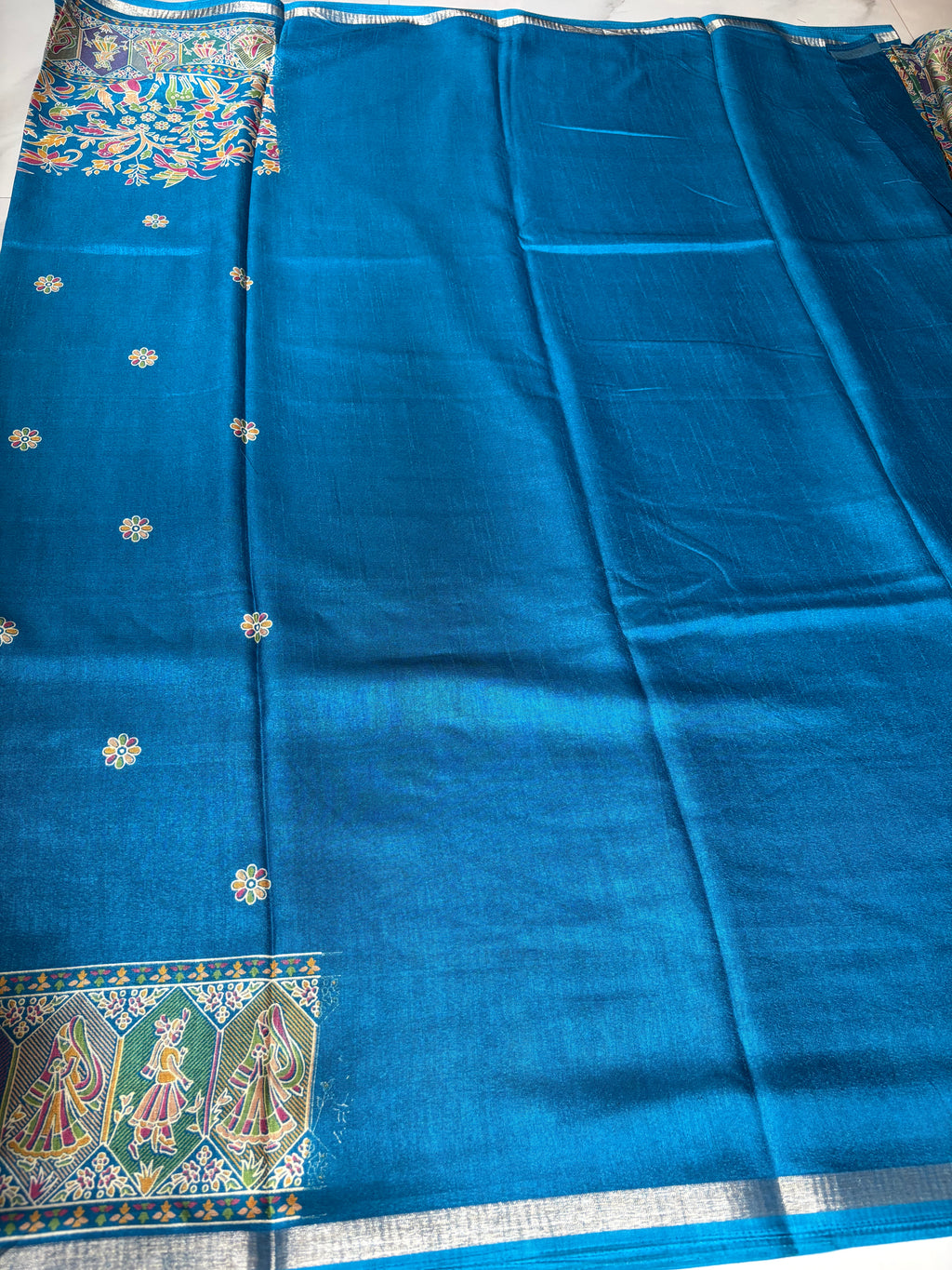 Elegant royal blue saree, beautifully adorned with intricate floral and bird-inspired prints and subtle silver edging.