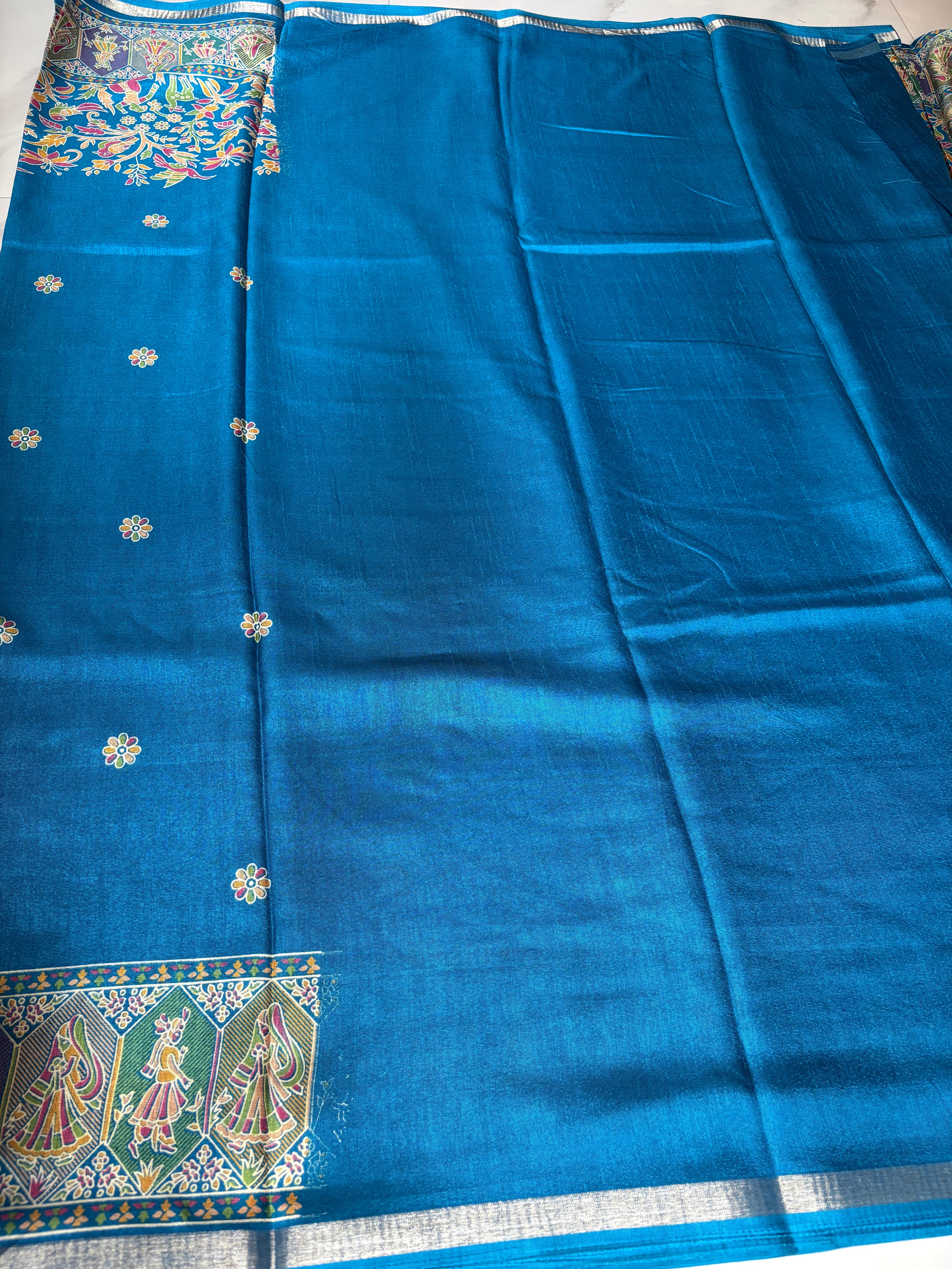 Elegant royal blue saree, beautifully adorned with intricate floral and bird-inspired prints and subtle silver edging.