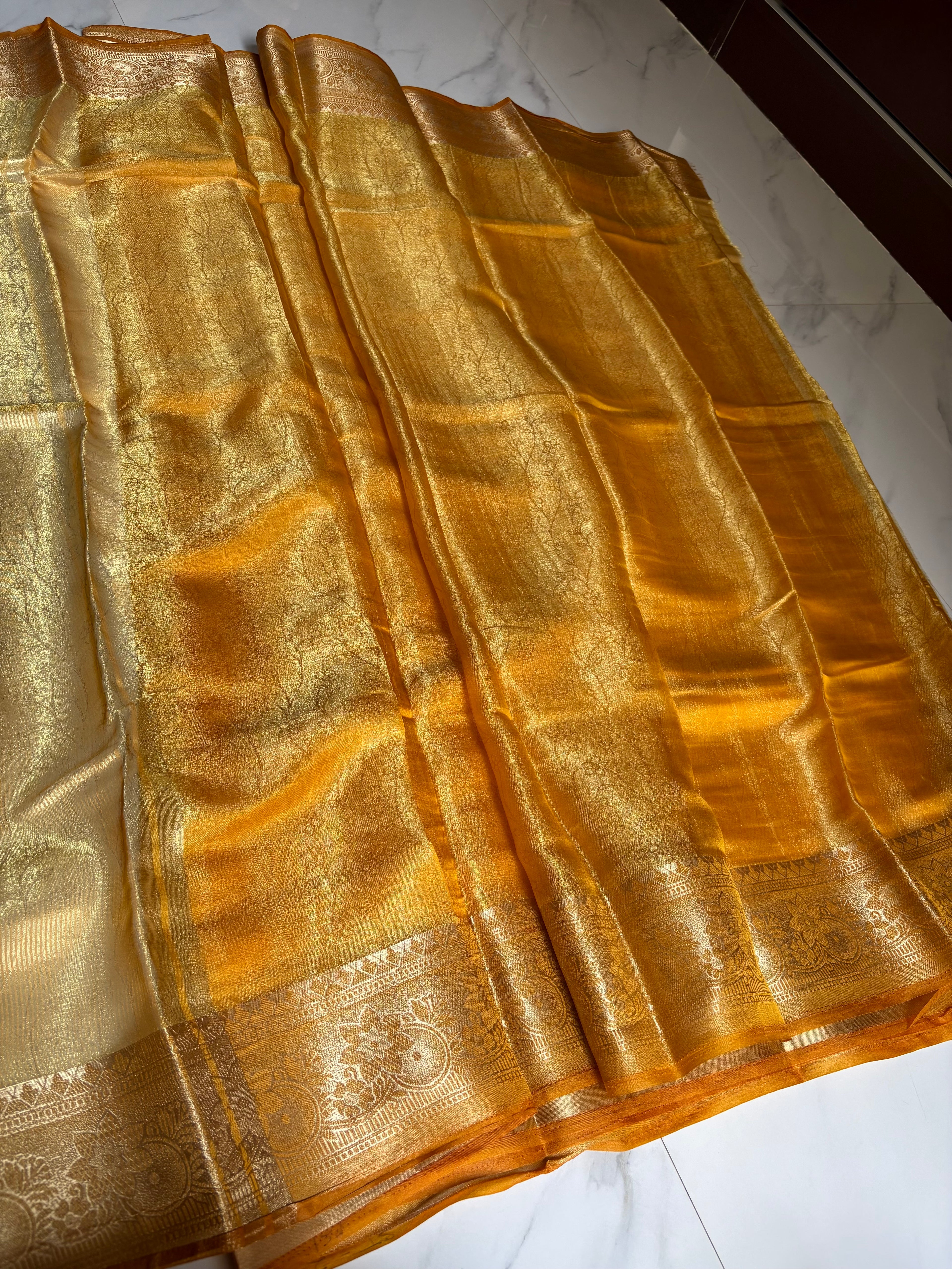 Elegant golden mustard Tissue saree, featuring a rich sheen and an intricately woven zari border.