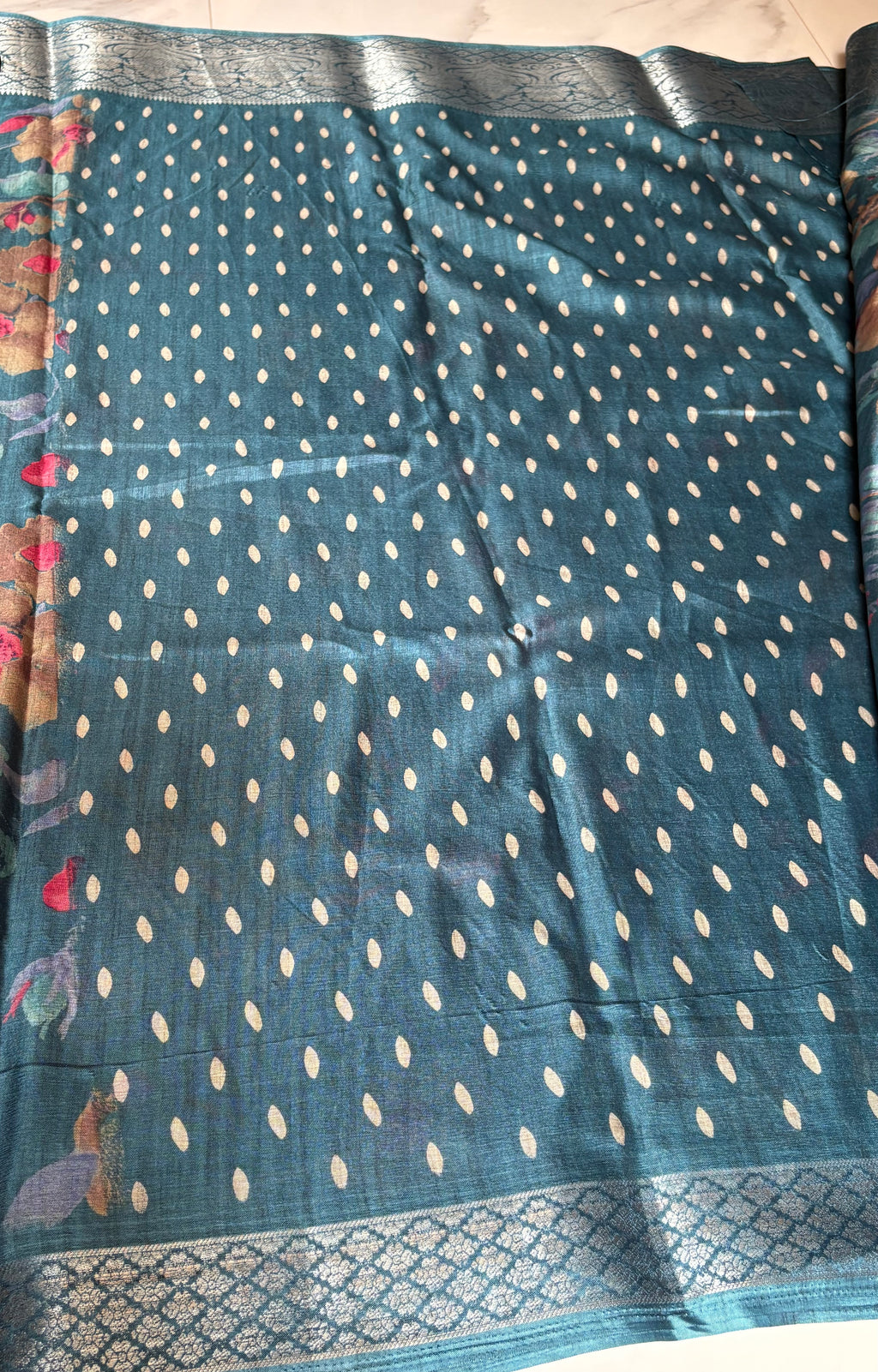 Elegant teal blue saree featuring vibrant multicolor floral prints. Finished with a rich Silver woven zari border- Satin Tissue Saree