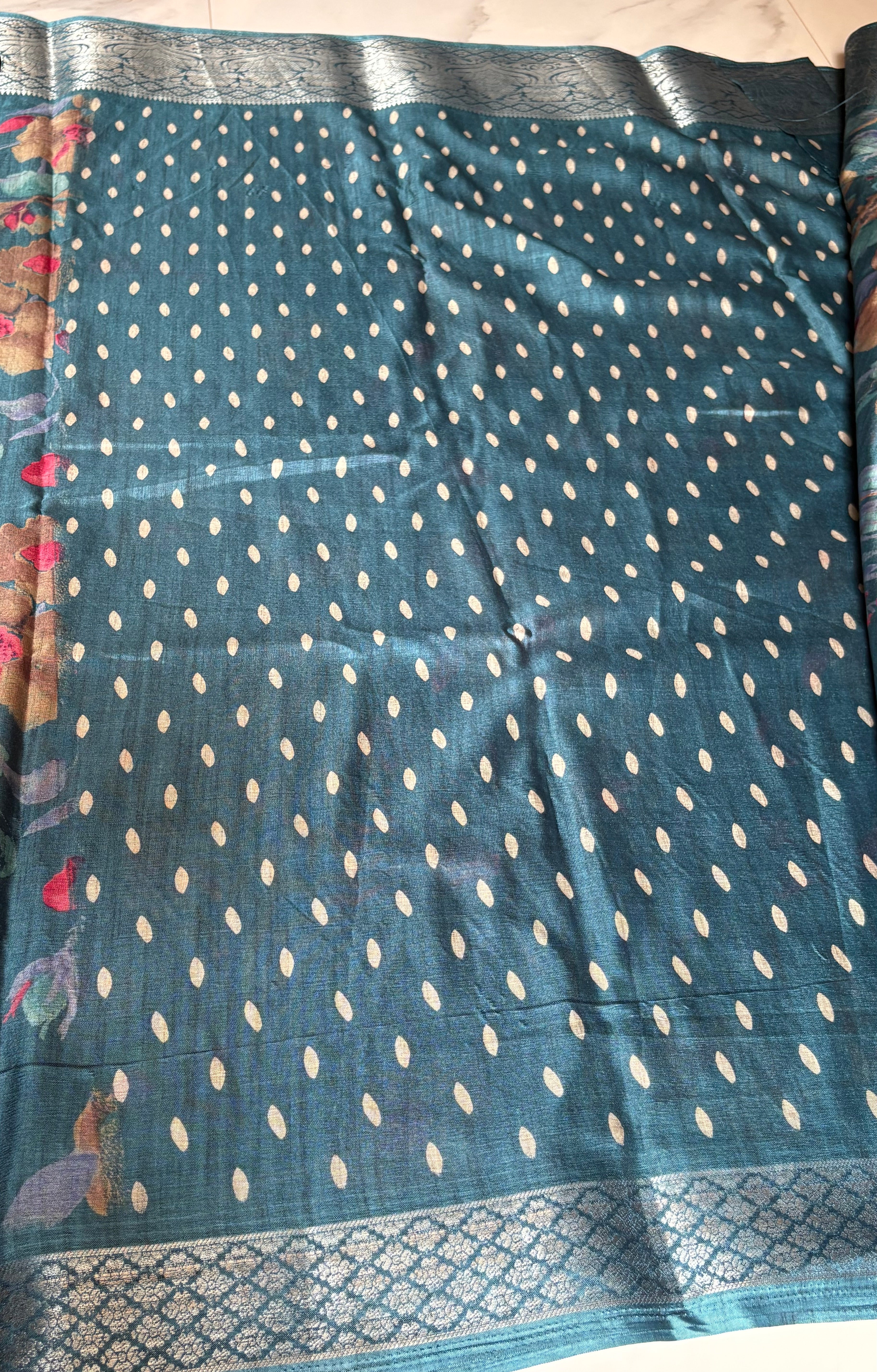Elegant teal blue saree featuring vibrant multicolor floral prints. Finished with a rich Silver woven zari border- Satin Tissue Saree