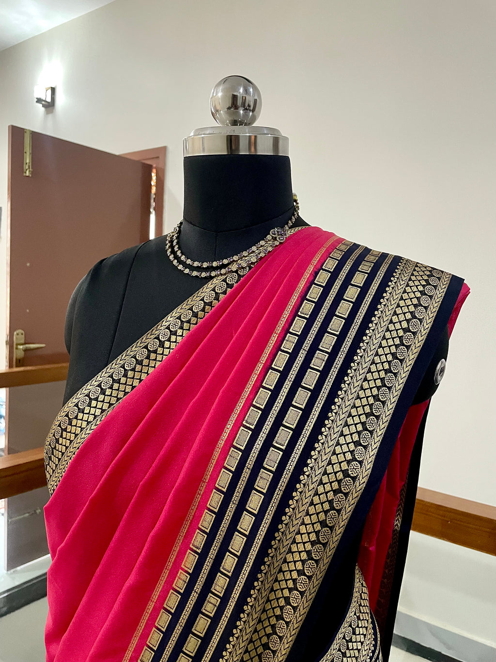 Beautiful Crepe Silk Saree with Striking Combination Of Bright Pink with a rich Navy Blue and gold border, giving it a Regal and Elegant look.