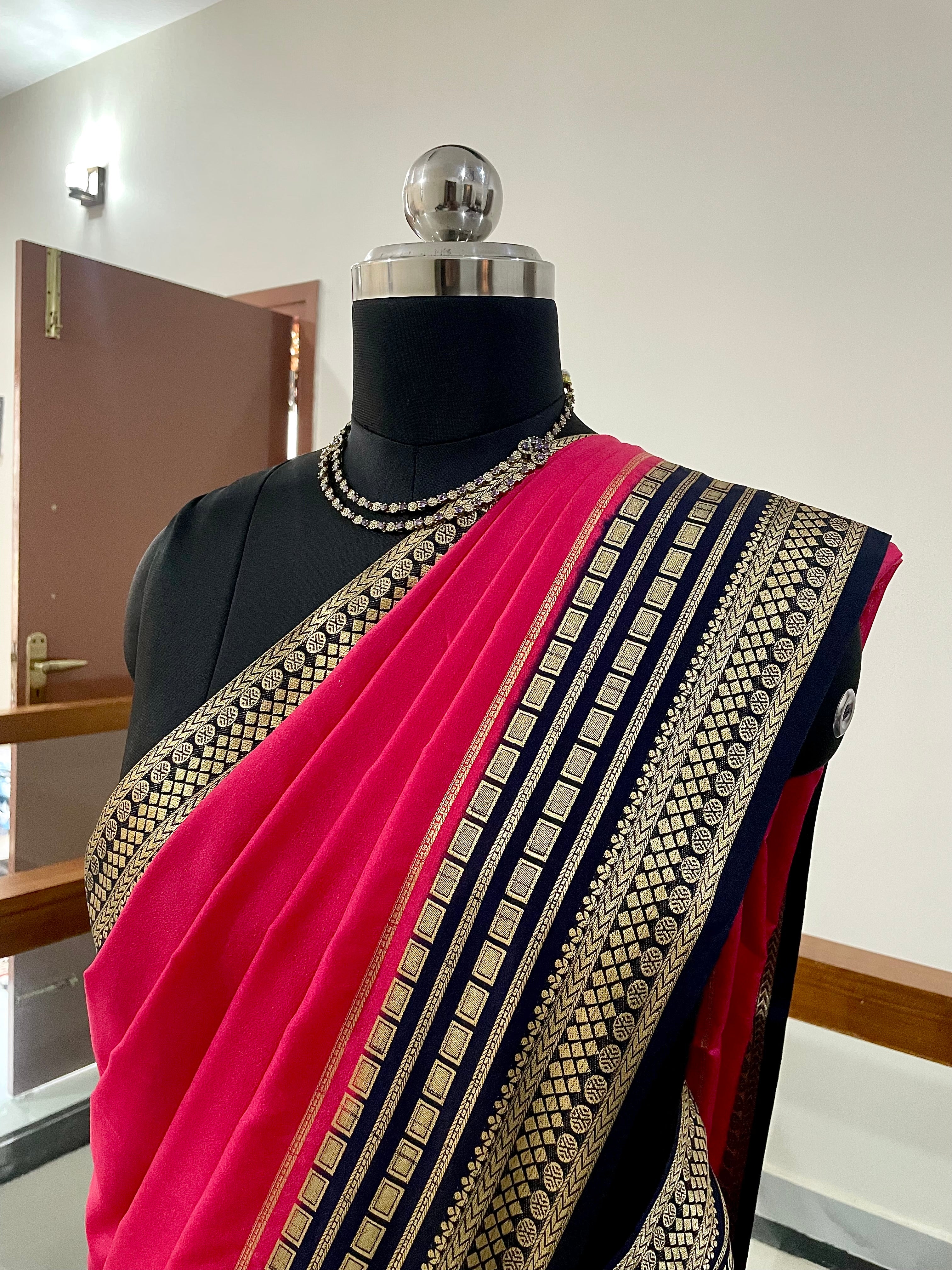 Beautiful Crepe Silk Saree with Striking Combination Of Bright Pink with a rich Navy Blue and gold border, giving it a Regal and Elegant look.