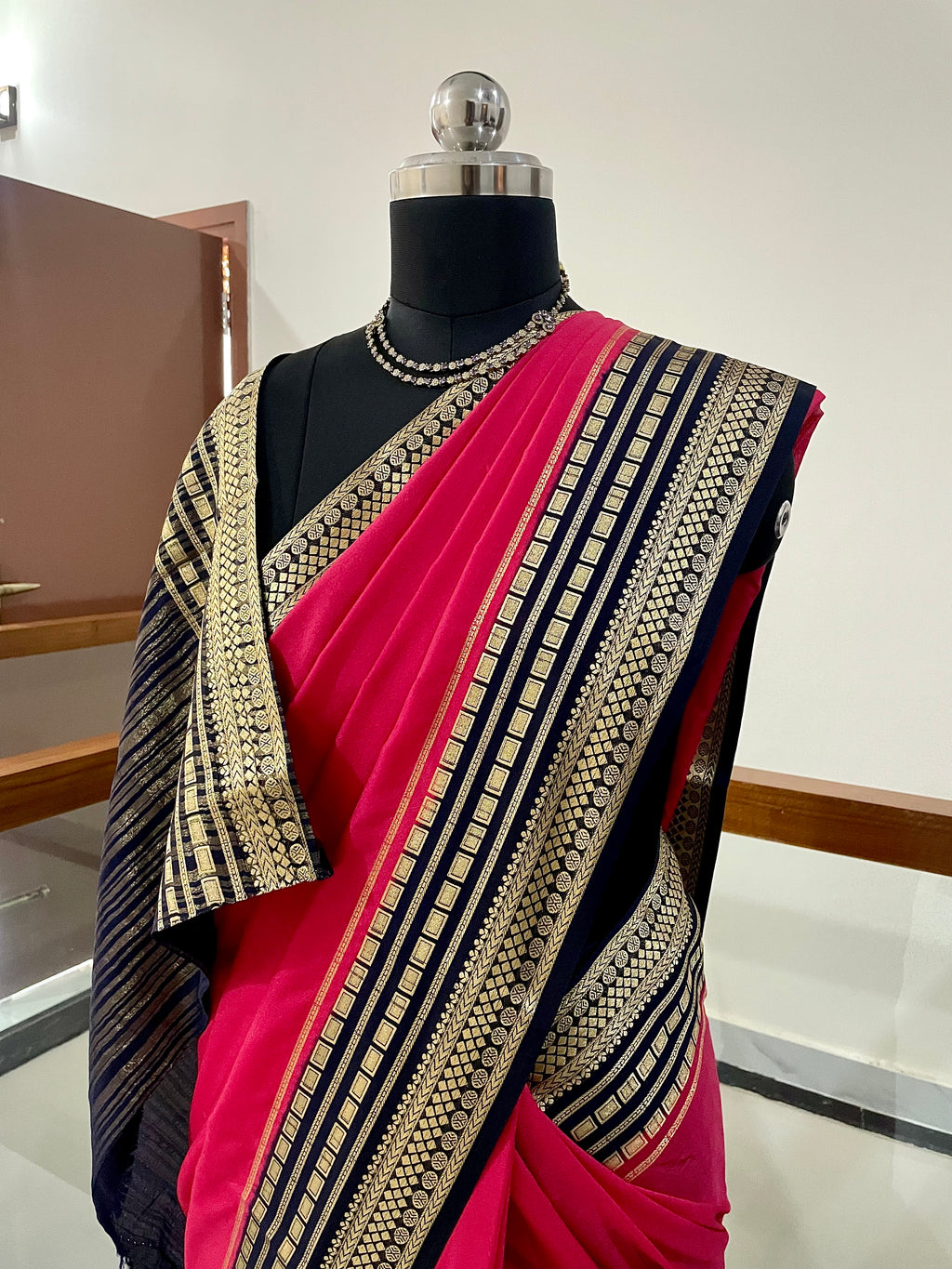 Beautiful Crepe Silk Saree with Striking Combination Of Bright Pink with a rich Navy Blue and gold border, giving it a Regal and Elegant look.