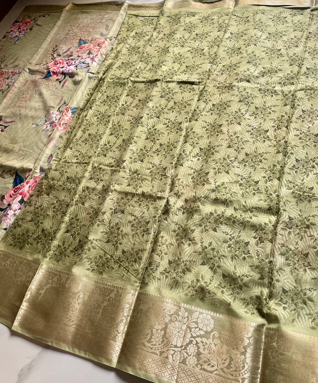 Elegant sage green saree featuring a graceful floral print in soft pink and lavender hues with rich woven zari border - Satin Tissue Saree (Copy)