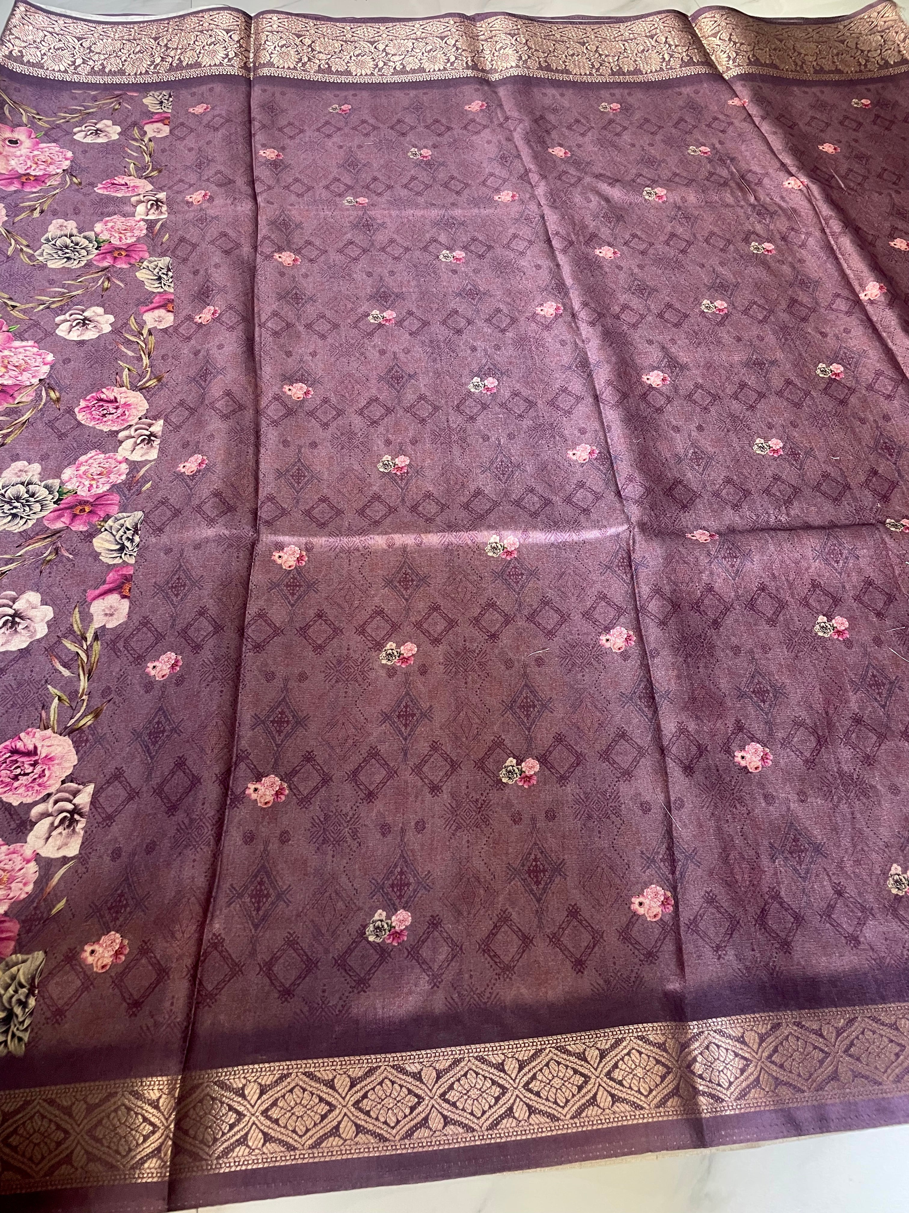 Elegant  purple floral printed saree features a beautiful all-over bloom pattern with rich woven zari border - Satin Tissue Saree