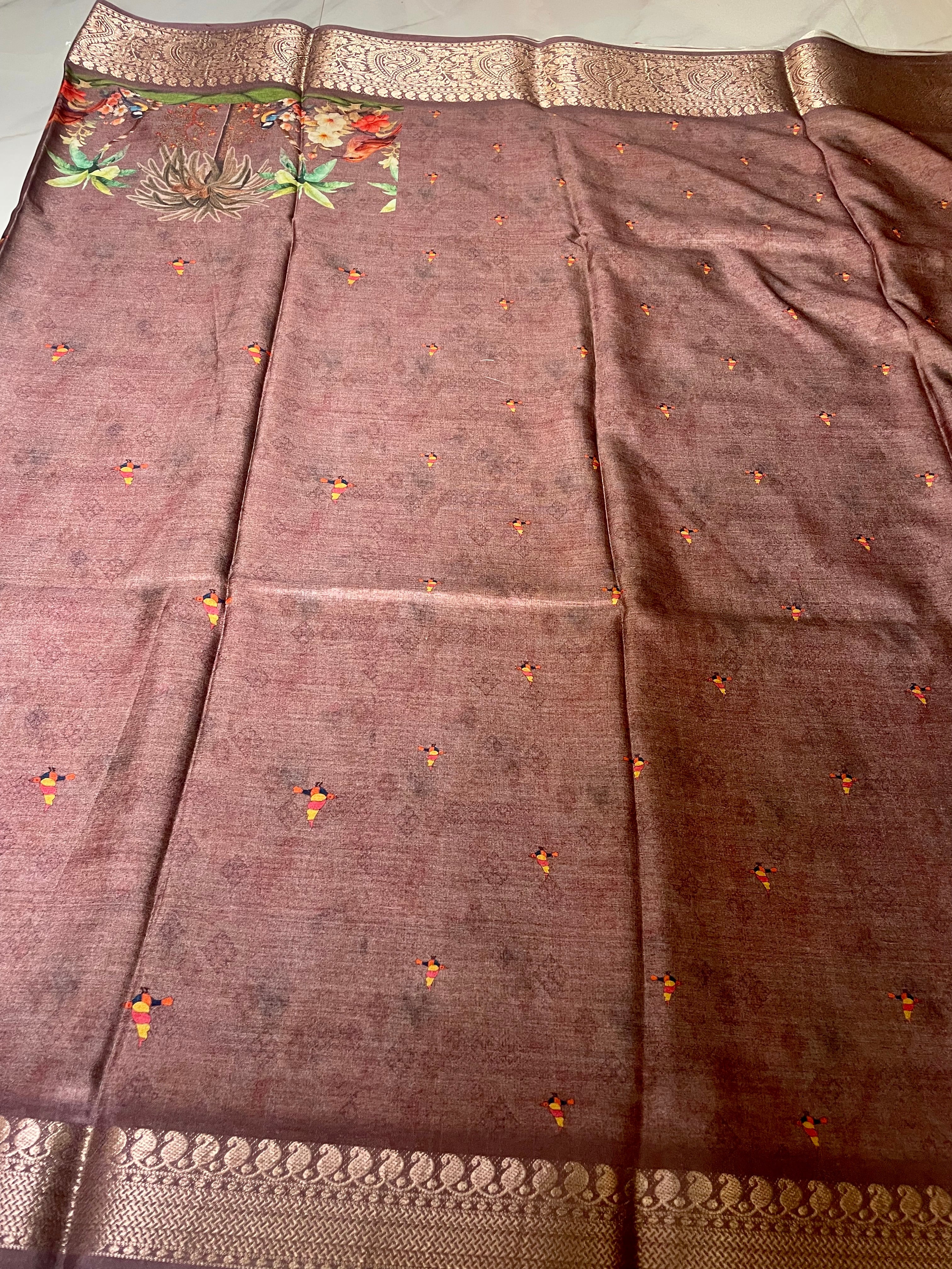 Elegant brown saree features a beautiful nature-inspired print with colorful birds, blooming flowers, and tropical treeswith rich zari border - Satin Tissue Saree